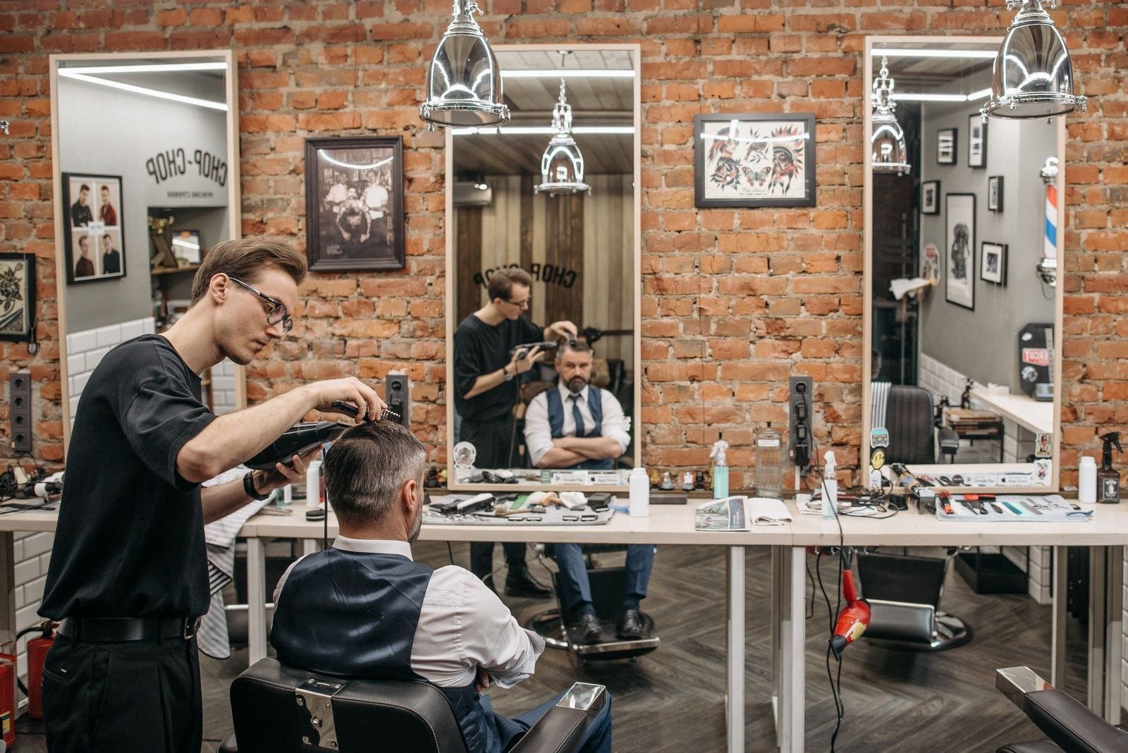 Barber cutting a client's hair in a brick-walled shop